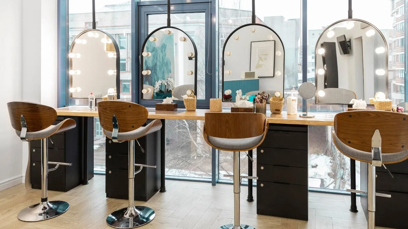 A bright, modern salon with lit vanity mirrors and styling stations